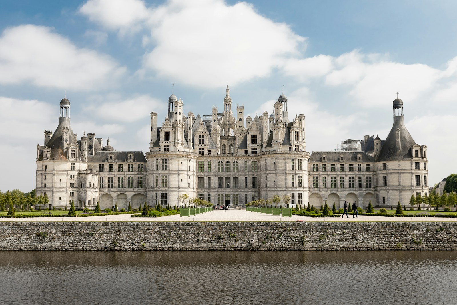 Château de Chambord, a grand French Renaissance castle, features distinctive turrets and manicured gardens, reflecting historical architecture by the riverbank.